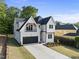 Stunning new construction home featuring a black garage door, a balcony, and green lawn at 1904 French Dr, Raleigh, NC 27612