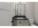 Modern powder room featuring a dark countertop, sleek fixtures, and a square mirror at 1904 French Dr, Raleigh, NC 27612