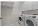 Functional laundry room with modern washer and dryer, white cabinets, and floating shelves at 2005 Delphi Way, Wake Forest, NC 27587