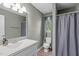 A bathroom features a single sink vanity, toilet, mirror, and a shower with gray shower curtain at 205 Twin Oaks Dr, Angier, NC 27501