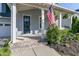 Inviting front porch with stone steps, white columns, American flag and manicured landscaping at 208 Vervain Way, Holly Springs, NC 27540