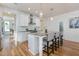 Modern kitchen with white cabinets, granite island, stainless appliances, and hardwood floors at 208 Vervain Way, Holly Springs, NC 27540
