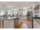 Open kitchen with granite countertops, stainless steel appliances, island seating and hardwood flooring at 208 Vervain Way, Holly Springs, NC 27540