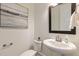 Charming powder room featuring stylish fixtures and a decorative mirror above pedestal sink at 208 Vervain Way, Holly Springs, NC 27540