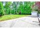 Expansive backyard featuring a driveway leading to a detached garage, surrounded by lush trees and greenery at 212 Ronaldsby Dr, Cary, NC 27511
