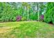 Well-manicured backyard featuring a spacious lawn, mature trees, and vibrant landscaping, offering a serene outdoor space at 212 Ronaldsby Dr, Cary, NC 27511