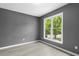 Bright bedroom with hardwood flooring, gray walls, and a large window with treeline views at 2402 Cynthia Dr, Durham, NC 27704