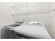 Clean laundry room with modern white washer, dryer, and two wire shelves for storage at 2402 Cynthia Dr, Durham, NC 27704