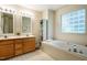 Bright bathroom features a double vanity, soaking tub, and unique glass block window for natural light at 244 Sweet Bay Pl, Carrboro, NC 27510