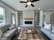 Bright living room with built-in shelving, electric fireplace, ceiling fan, and hardwood floors with gray trim at 257 Bluejay St, Clayton, NC 27520