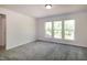 A bedroom featuring three windows with natural light and neutral carpeting at 261 White Oak Ridge Dr, Garner, NC 27529