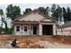 An unfinished exterior of a one-story home with an attached garage under construction with tree line background at 31 Goldenrod Loop, Clayton, NC 27520