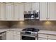 Close-up of kitchen with stainless steel appliances, granite countertops, and custom white cabinets at 312 Troon Village Ln, Cary, NC 27511