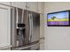 Close-up of stainless steel refrigerator and freezer with a small television mounted on the wall at 312 Troon Village Ln, Cary, NC 27511