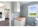 Bright laundry room featuring plenty of counter space, overhead storage, and a scenic window view at 3805 Euliss Rd, Burlington, NC 27215