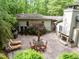 Aerial view of the private backyard featuring a large brick patio with an outdoor fireplace and lounge chairs at 3915 Nottaway Rd, Durham, NC 27707