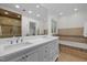 Bathroom featuring a double sink vanity, soaking tub with tile surround, and a glass enclosed shower at 3915 Nottaway Rd, Durham, NC 27707