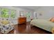 Bedroom with hardwood floors, sitting chair, dresser, and windows with backyard view at 3915 Nottaway Rd, Durham, NC 27707