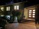 Home exterior at twilight with brick steps, decorative plants, modern door with sidelights, and landscape lighting at 3915 Nottaway Rd, Durham, NC 27707