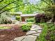 Lush front yard featuring a stone path leading to a home nestled within a grove of trees at 3915 Nottaway Rd, Durham, NC 27707