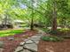 Picturesque front yard with a stone pathway, lush landscaping, and mature trees creating a serene atmosphere at 3915 Nottaway Rd, Durham, NC 27707