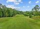 Expansive view of lush green golf course lined with trees under a blue sky at 3915 Nottaway Rd, Durham, NC 27707