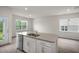Open kitchen featuring stainless steel dishwasher, white shaker cabinets, large window and luxury vinyl plank flooring at 400 Ember St, Sanford, NC 27330