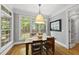Bright dining room featuring a wooden table, hardwood floors, and large windows overlooking a lush backyard at 402 Troycott Pl, Cary, NC 27519