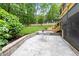 Stone patio with seating area and landscaped retaining wall lead to lush, private backyard at 4215 Cobscook Dr, Durham, NC 27707