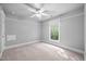 Neutral bedroom featuring plush carpeting, ceiling fan, and large window with natural light at 4405 New Brighton Dr, Apex, NC 27539
