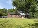 Grassy backyard with mature trees with direct access to brick-based house at 5026 Gatewood Drive Dr, Durham, NC 27712
