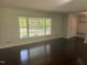Spacious living room with hardwood floors, a large window, and a glimpse of the mudroom at 5026 Gatewood Drive Dr, Durham, NC 27712