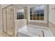 Bright bathroom featuring a soaking tub, glass-enclosed shower, and a large window at 615 Prides Crsg Xing, Rolesville, NC 27571