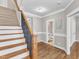 Elegant hallway featuring hardwood floors, staircase with wrought iron railing, and access to a half bathroom at 615 Prides Crsg Xing, Rolesville, NC 27571