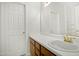 Bright bathroom featuring a single sink vanity with wood cabinets, a large mirror, and a door at 6539 Clarksdale Ln, Durham, NC 27713