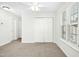Bright bedroom featuring a ceiling fan, window with blinds, neutral carpet, and a double door closet at 6539 Clarksdale Ln, Durham, NC 27713