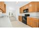 Well-lit kitchen featuring wooden cabinets, black appliances, and easy access to other rooms in the house at 6539 Clarksdale Ln, Durham, NC 27713