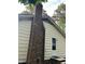 Close up of a brick chimney extending from a home with yellow siding, dark roof and white door at 7412 Barberry Ct, Raleigh, NC 27615