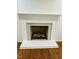 Elegant fireplace in a room with hardwood floors, featuring a white mantel and filled with firewood at 7412 Barberry Ct, Raleigh, NC 27615