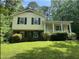 Two-story home with yellow siding, brick foundation, covered front porch, and manicured lawn surrounded by lush greenery at 7412 Barberry Ct, Raleigh, NC 27615