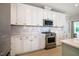 Bright kitchen featuring white cabinets, stainless steel appliances, and white backsplash at 83 Vandalia Ave, Chapel Hill, NC 27516
