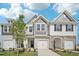 Charming townhome exterior featuring a mix of siding and stone accents, complemented by a well-manicured lawn and blue skies at 908 Kensley Grove Ln # 68, Fuquay Varina, NC 27526