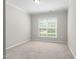 Bright bedroom featuring neutral walls, plush carpet, and a window offering natural light and outdoor views at 10 Currituck Ln, Durham, NC 27703