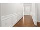 Hallway with hardwood floors, paneled walls, white trim, and entry door leading to the outside at 10 Currituck Ln, Durham, NC 27703
