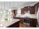 Modern kitchen featuring stainless steel appliances, granite countertops, and wooden cabinetry at 10 Currituck Ln, Durham, NC 27703