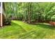Large, beautifully landscaped backyard with mature trees and green grass at 1003 Fairfax Woods Dr, Apex, NC 27502