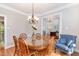 Elegant dining room featuring a glass-top table, wood chairs, and chandelier lighting at 1003 Fairfax Woods Dr, Apex, NC 27502
