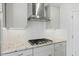 Close-up of the kitchen featuring granite countertops, stainless steel range hood, and sleek gas cooktop at 1005 Whispering Creek Ct, Knightdale, NC 27545