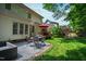 Charming backyard with stone patio, outdoor seating, green grass, and mature landscaping, perfect for relaxation at 10113 San Remo Pl, Wake Forest, NC 27587