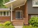 Home featuring a brick entrance, a covered front porch, and manicured shrubs at 1024 Chalmers St, Durham, NC 27707